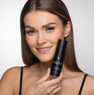 Modelo sonriente sosteniendo el champú Lash & Brow