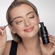Modelo rubia sonriente usando champú para pestañas